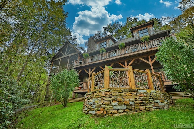 rear view of property with a deck, a sunroom, and a lawn