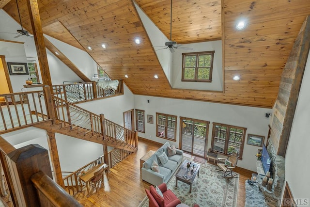 living room with high vaulted ceiling, beamed ceiling, ceiling fan, wood ceiling, and light wood-type flooring