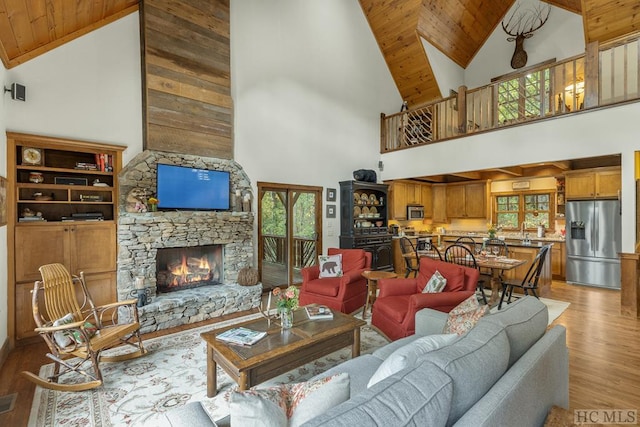 living room featuring wooden ceiling, a fireplace, high vaulted ceiling, and light hardwood / wood-style floors