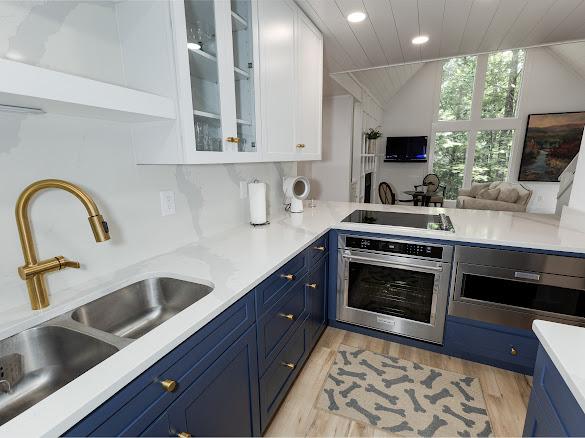 49 Kiwi Ln Unit 14, Sapphire, NC 28774 - kitchen featuring stainless steel oven, blue cabinetry, black electric stovetop, white cabinetry, and vaulted ceiling