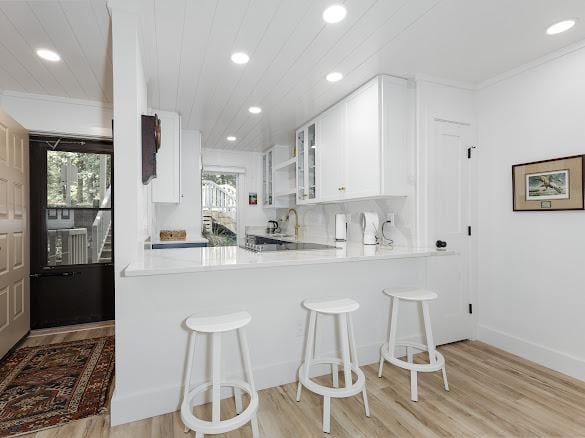 49 Kiwi Ln Unit 14, Sapphire, NC 28774 - kitchen with light wood-type flooring, glass insert cabinets, recessed lighting, a breakfast bar area, and healthy amount of natural light