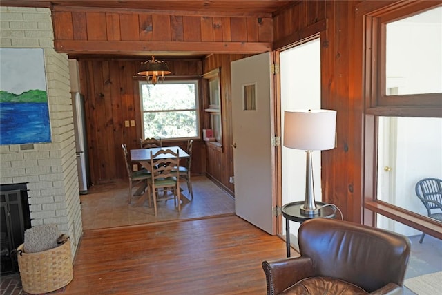 dining space with wood finished floors, a brick fireplace, and wood walls