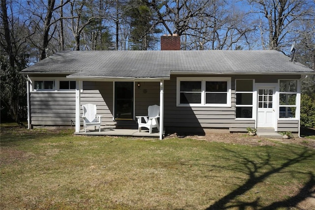 back of property with a yard, a chimney, and a patio area