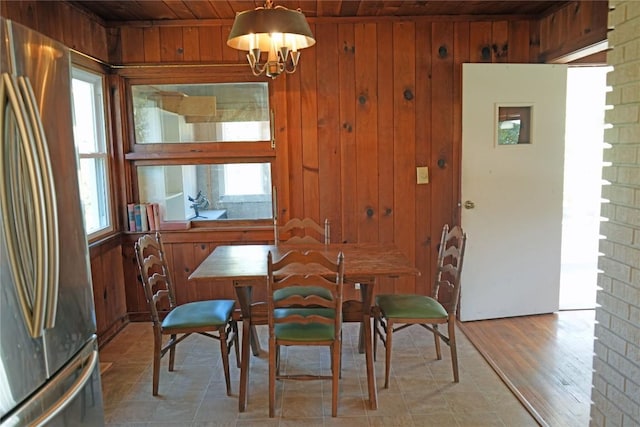 dining space featuring an inviting chandelier, wooden ceiling, and wood walls