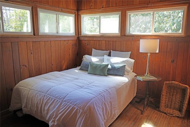 bedroom featuring multiple windows, wood finished floors, and wood walls