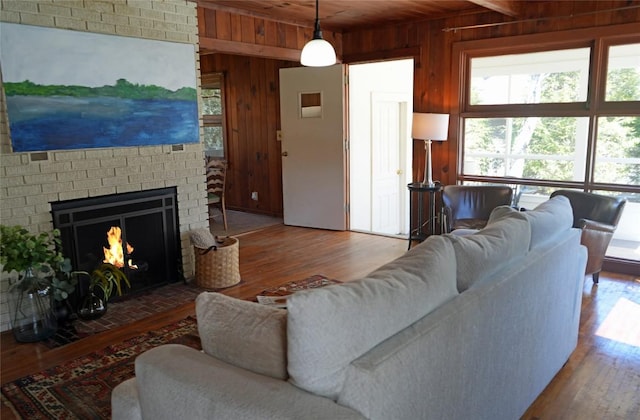 living room featuring wooden walls, a fireplace, wooden ceiling, and wood finished floors