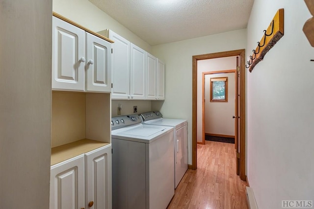 laundry area featuring cabinets, washing machine and dryer, light hardwood / wood-style flooring, and a textured ceiling