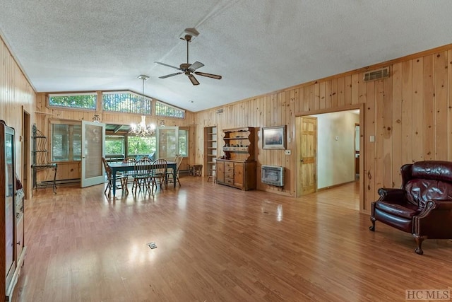 dining area with hardwood / wood-style flooring, lofted ceiling, heating unit, and ceiling fan with notable chandelier