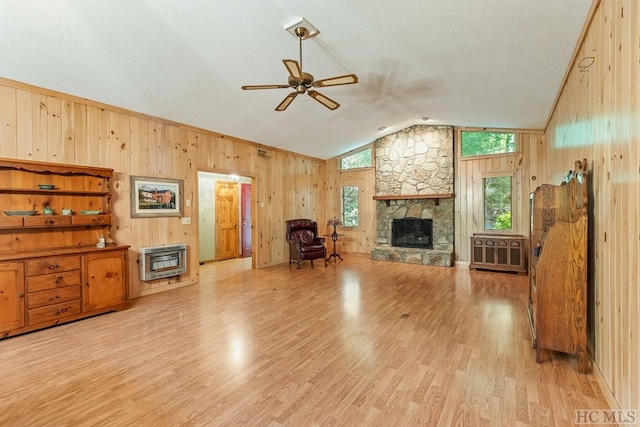 living room featuring lofted ceiling, light wood-type flooring, heating unit, and a fireplace