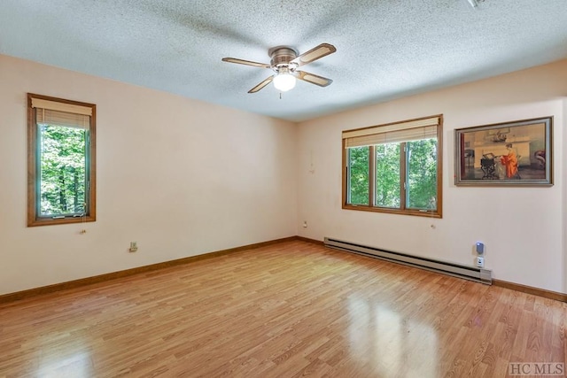 spare room featuring ceiling fan, light hardwood / wood-style floors, a textured ceiling, and baseboard heating