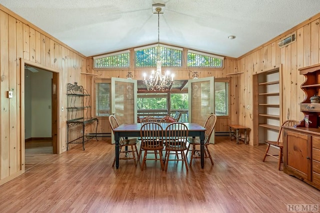 dining area with baseboard heating, a textured ceiling, vaulted ceiling, a chandelier, and light wood-type flooring