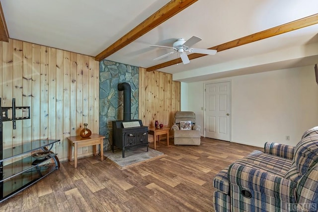 living room featuring beamed ceiling, wooden walls, hardwood / wood-style floors, and a wood stove