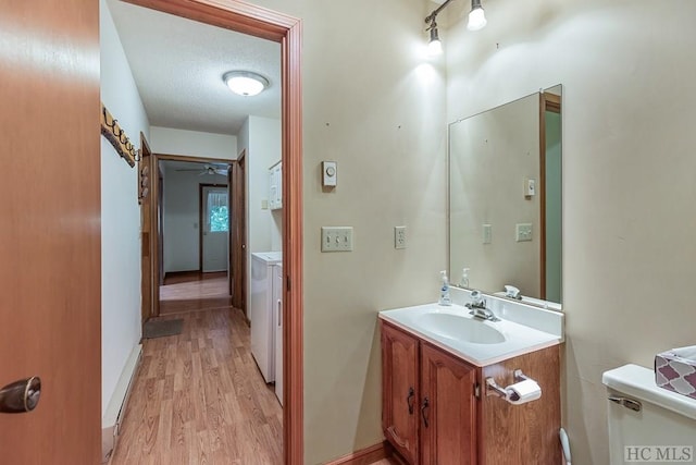 bathroom featuring toilet, wood-type flooring, washer and dryer, a textured ceiling, and vanity