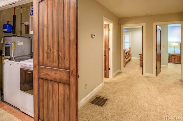 laundry room with electric water heater, light colored carpet, and washer and dryer