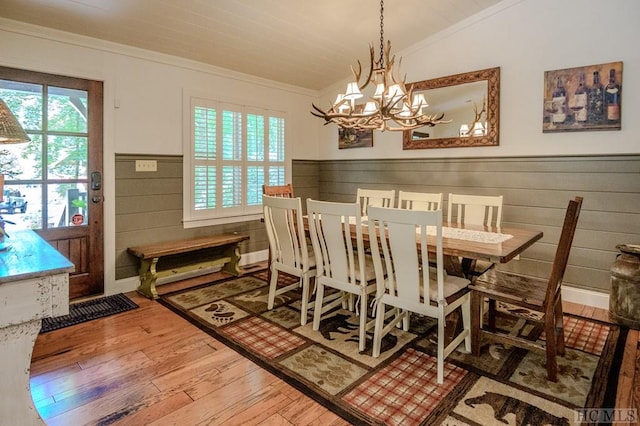 dining space with lofted ceiling, hardwood / wood-style floors, ornamental molding, and a chandelier