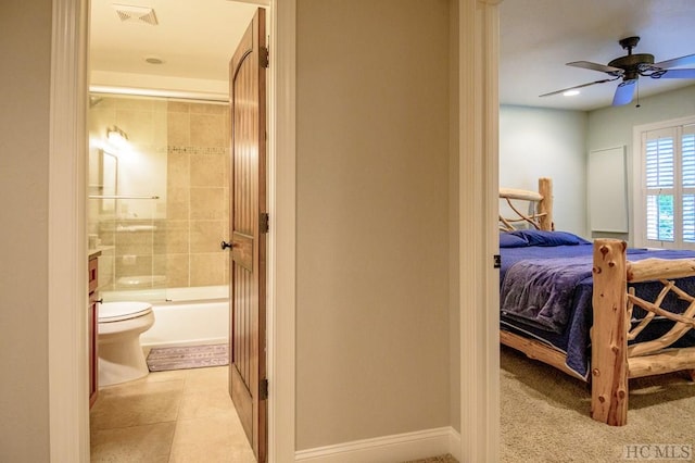 bedroom with ensuite bathroom, light tile patterned flooring, and ceiling fan