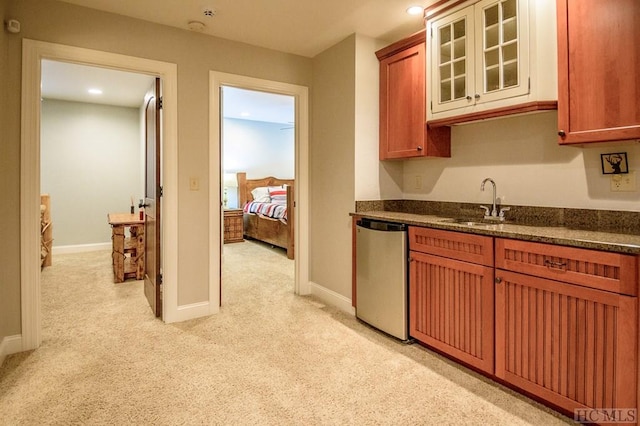 kitchen featuring stainless steel dishwasher, sink, and light carpet