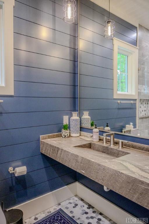 bathroom featuring tile patterned floors, sink, and wood walls