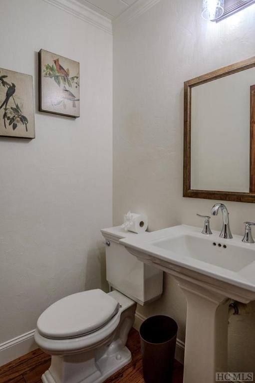 bathroom with crown molding, toilet, and hardwood / wood-style flooring