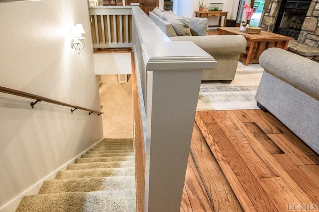 staircase with wood-type flooring and a fireplace