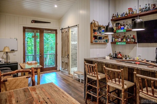 bar with wood-type flooring, vaulted ceiling, wooden walls, and french doors