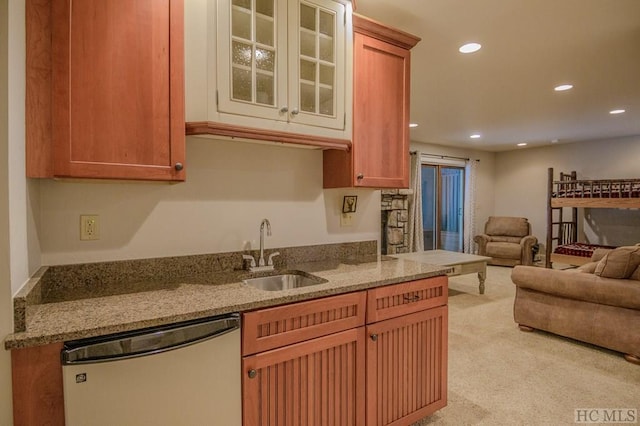 kitchen with light stone counters, sink, light colored carpet, and dishwasher