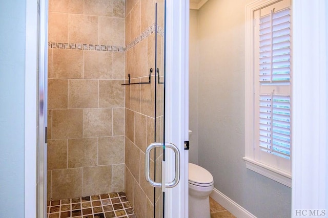 bathroom featuring a shower with door and toilet