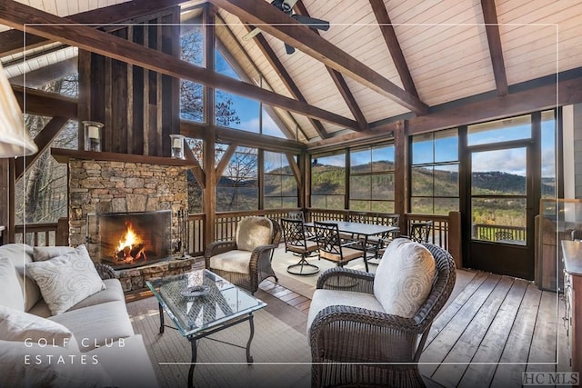 sunroom featuring vaulted ceiling with beams and a stone fireplace