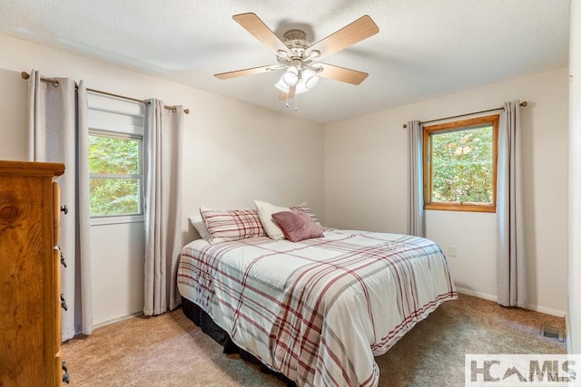carpeted bedroom featuring baseboards, visible vents, ceiling fan, and multiple windows