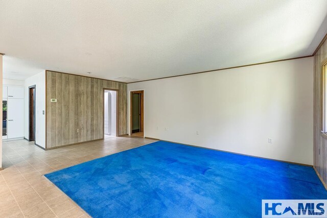 unfurnished room with wooden walls and baseboards
