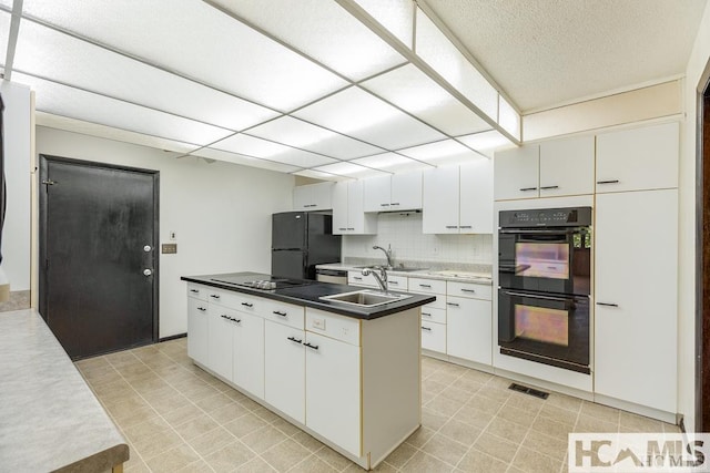 kitchen featuring white cabinetry, a sink, visible vents, black appliances, and a center island with sink