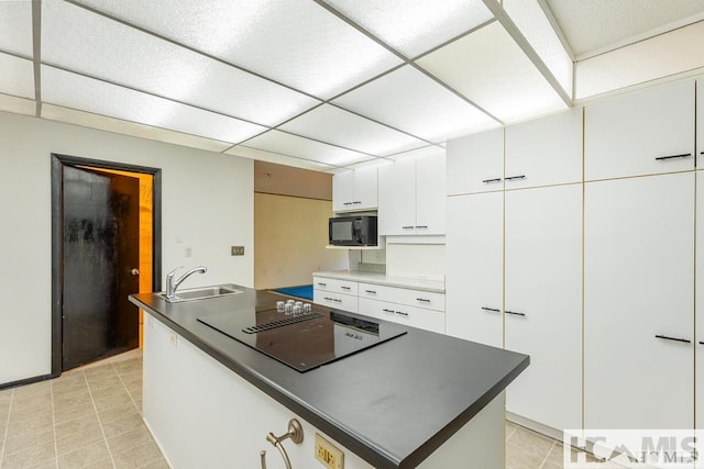 kitchen featuring white cabinets, black appliances, dark countertops, and a sink