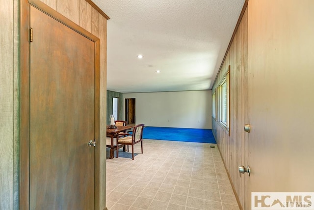 hall with a textured ceiling, recessed lighting, and baseboards