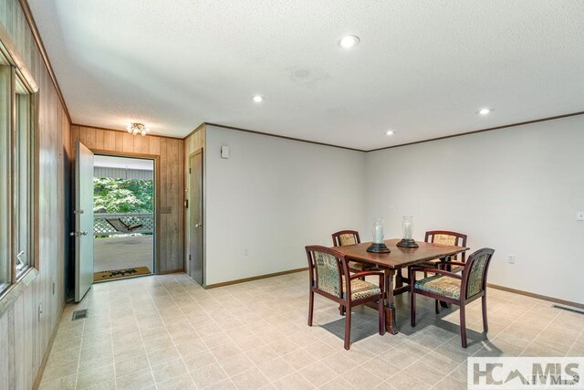 dining space featuring baseboards, visible vents, wooden walls, and a textured ceiling