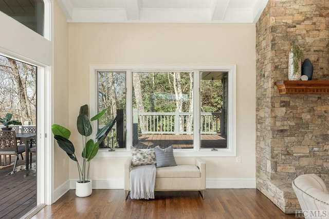 living area featuring beam ceiling, dark wood-type flooring, and ornamental molding