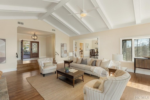 living room featuring ceiling fan with notable chandelier, light wood-type flooring, and vaulted ceiling with beams