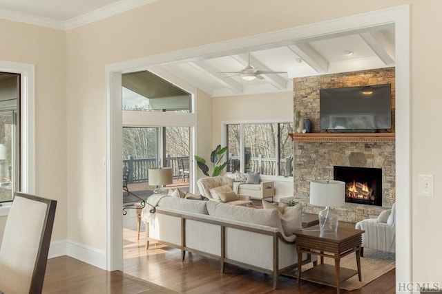 living room featuring ceiling fan, a stone fireplace, dark hardwood / wood-style floors, and beam ceiling