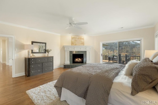 bedroom with crown molding, wood-type flooring, access to outside, ceiling fan, and a fireplace