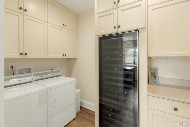 laundry area featuring wine cooler, cabinets, light hardwood / wood-style floors, and washing machine and dryer