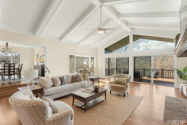 sunroom featuring vaulted ceiling with beams and ceiling fan with notable chandelier