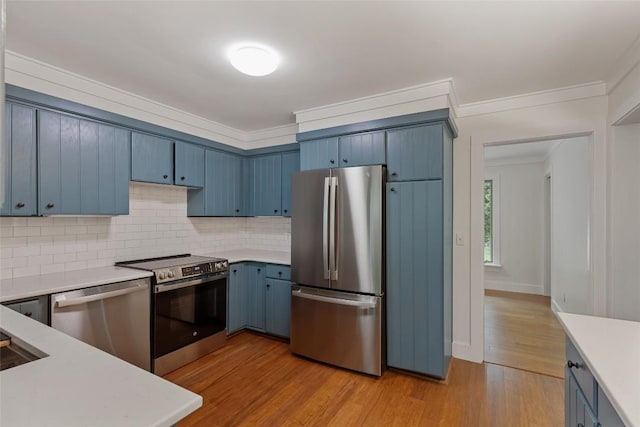 66 Hemlock Ln, Highlands, NC 28741 - kitchen with appliances with stainless steel finishes, blue cabinetry, light countertops, decorative backsplash, and ornamental molding
