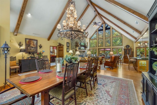 dining area with visible vents, wood finished floors, beam ceiling, high vaulted ceiling, and ceiling fan with notable chandelier