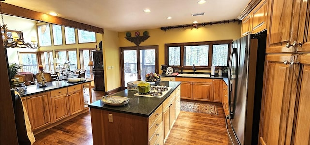 kitchen featuring white cooktop, a center island, freestanding refrigerator, wood finished floors, and visible vents
