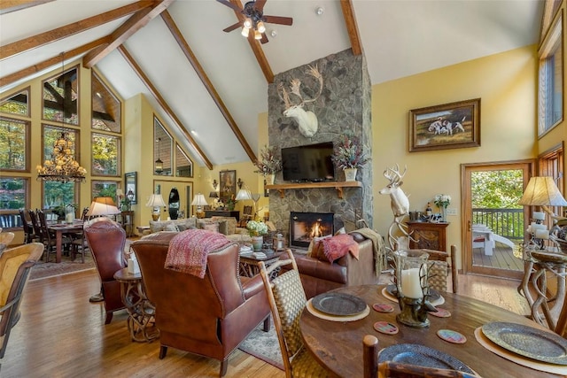 living area featuring ceiling fan, a fireplace, high vaulted ceiling, wood finished floors, and beamed ceiling
