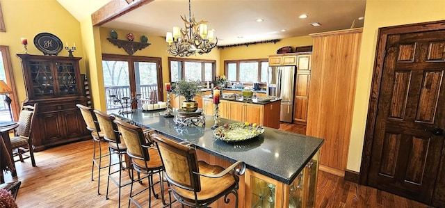 kitchen with dark countertops, stainless steel fridge, recessed lighting, wood finished floors, and a kitchen island