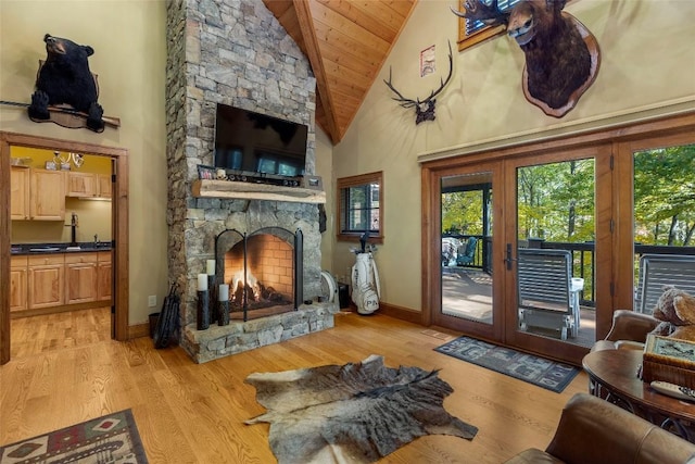 living area featuring a fireplace, high vaulted ceiling, french doors, light wood-type flooring, and wood ceiling