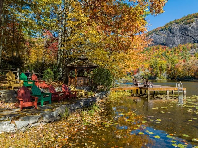 dock area with a gazebo, a wooded view, and a water and mountain view