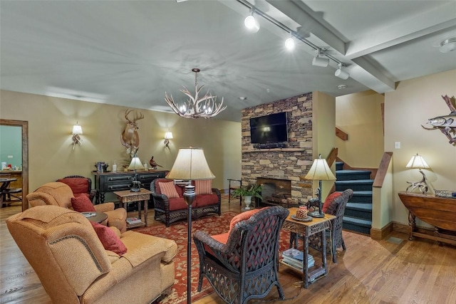 living room with stairway, rail lighting, wood finished floors, and a notable chandelier