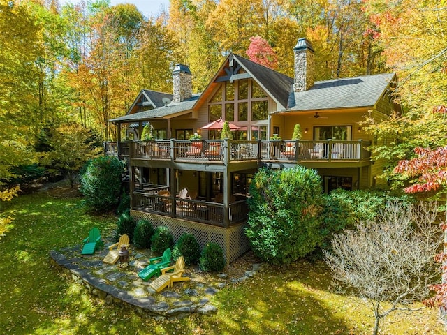 rear view of property featuring a chimney, a shingled roof, and a deck