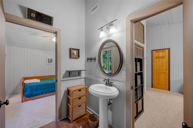 bathroom with a ceiling fan, visible vents, wood walls, wood finished floors, and a sink